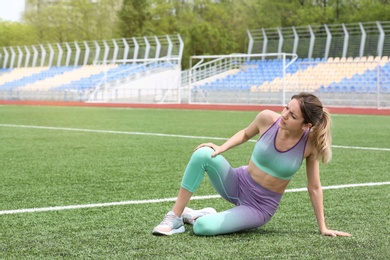 Woman in sportswear suffering from knee pain at soccer field