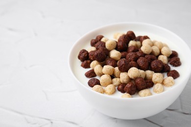 Photo of Breakfast cereal. Tasty corn balls with milk in bowl on white textured table, closeup. Space for text