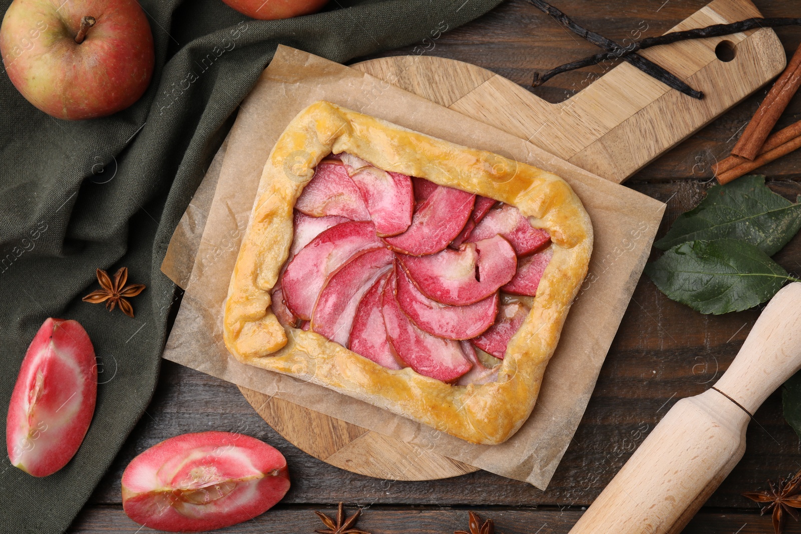 Photo of Delicious galette with apples, spices and fruit on wooden table, flat lay