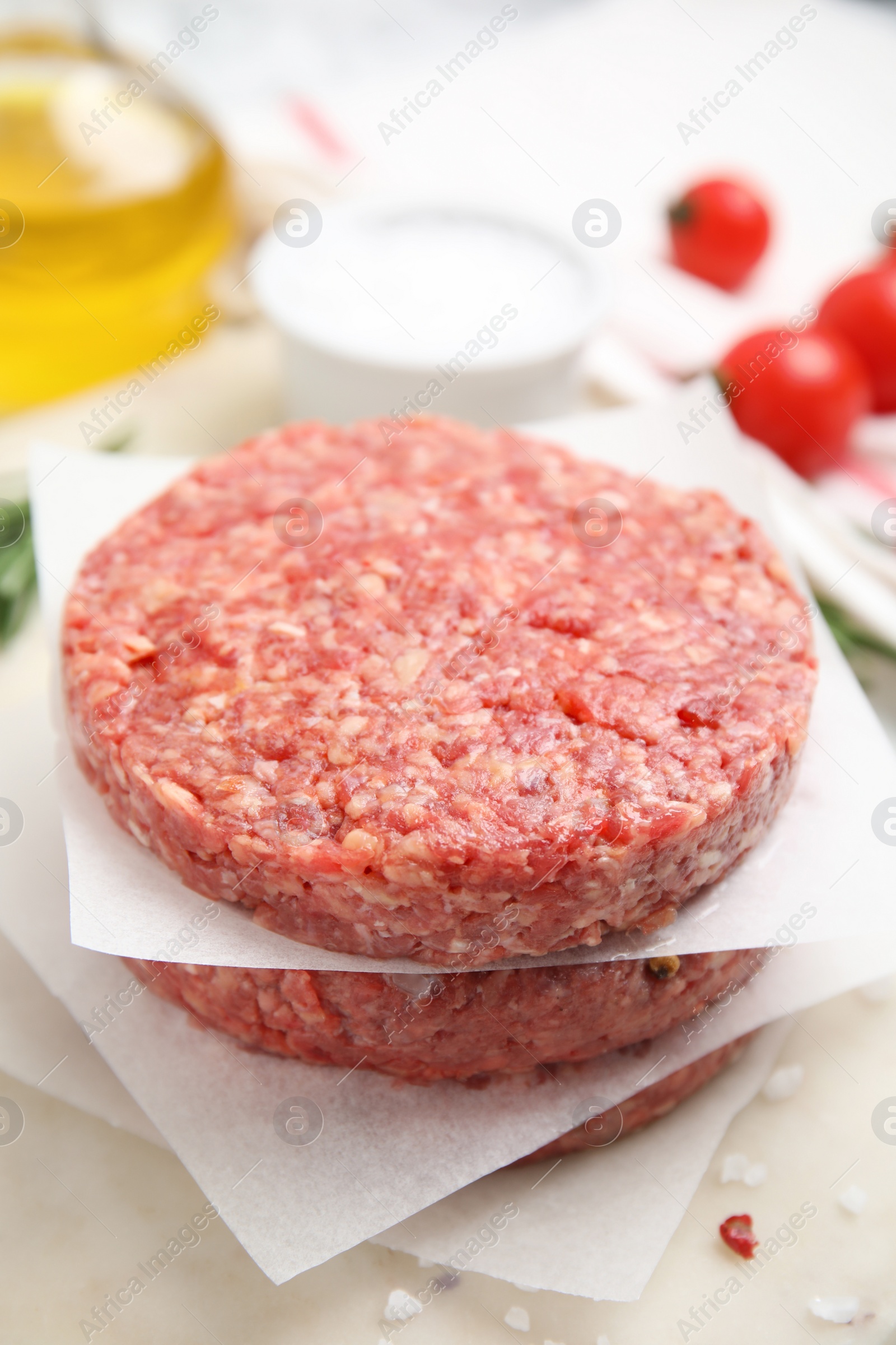 Photo of Raw hamburger patties with rosemary and salt on board, closeup