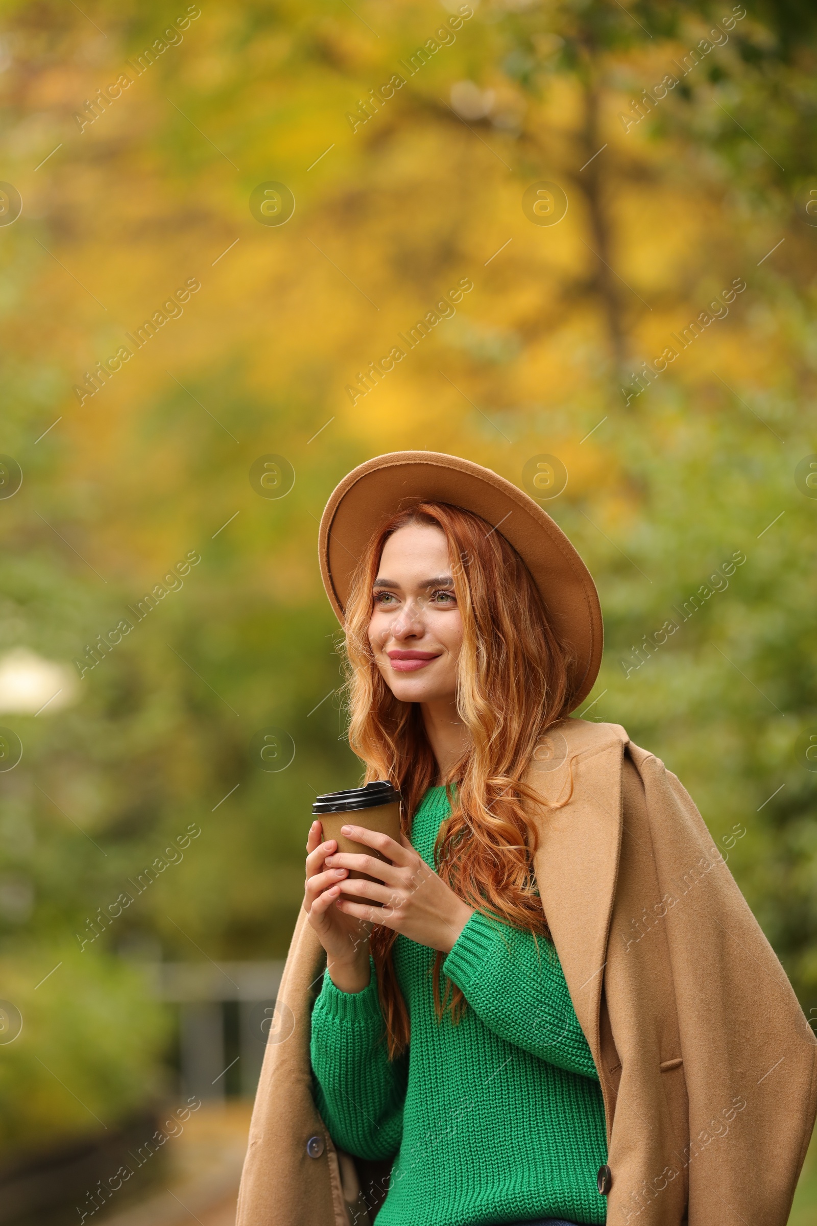 Photo of Smiling woman with paper cup in autumn park