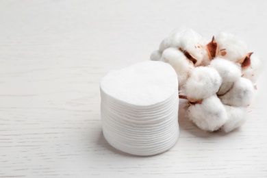 Composition with cotton pads and flowers on white wooden background. Space for text