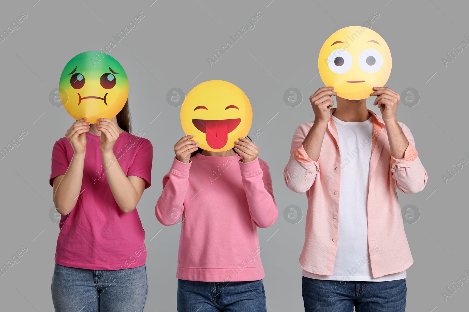 Photo of People covering faces with emoticons on grey background