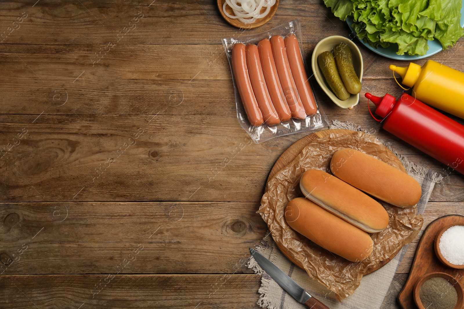 Photo of Different tasty ingredients for hot dog on wooden table, flat lay. Space for text