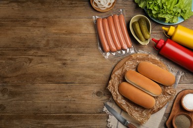 Different tasty ingredients for hot dog on wooden table, flat lay. Space for text
