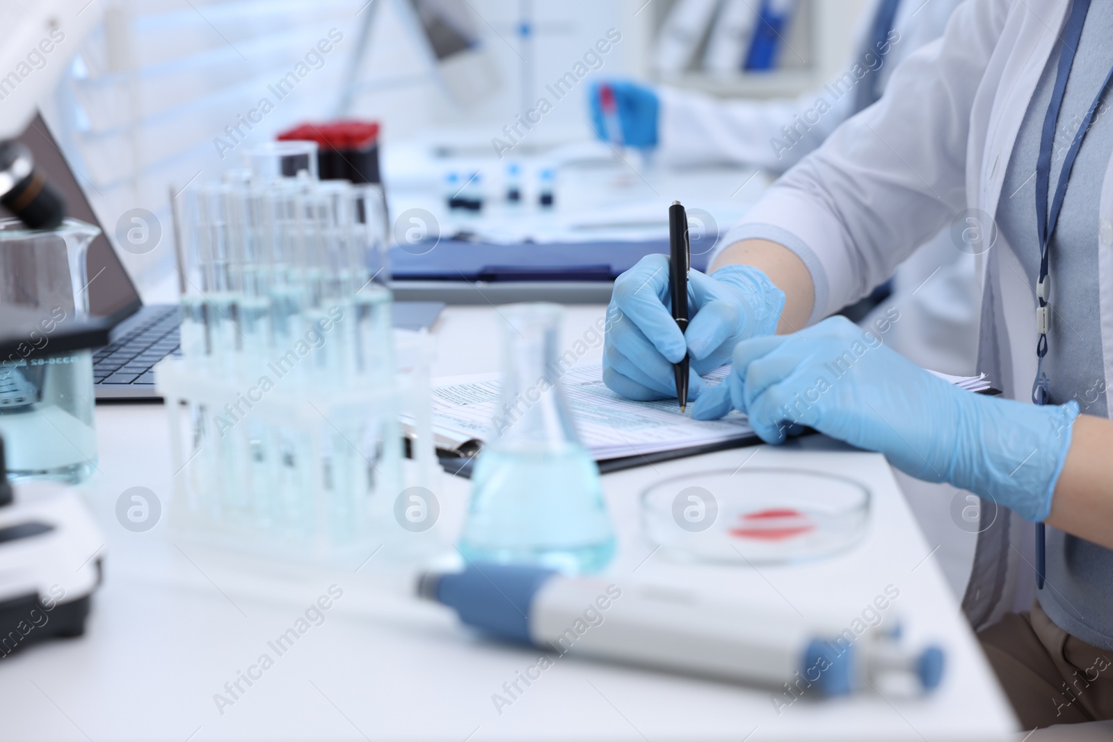 Photo of Laboratory worker working at white table, closeup