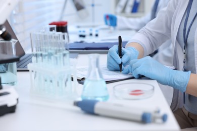 Photo of Laboratory worker working at white table, closeup