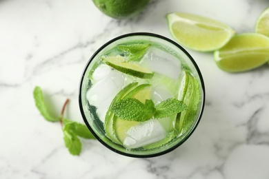 Refreshing beverage with mint and lime in glass on table, top view