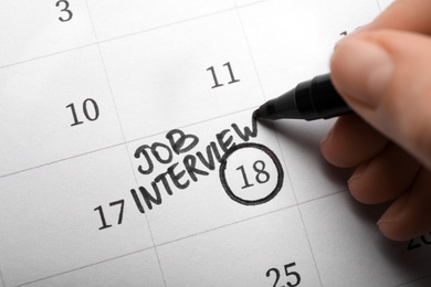 Photo of Woman marking date of job interview in calendar, closeup