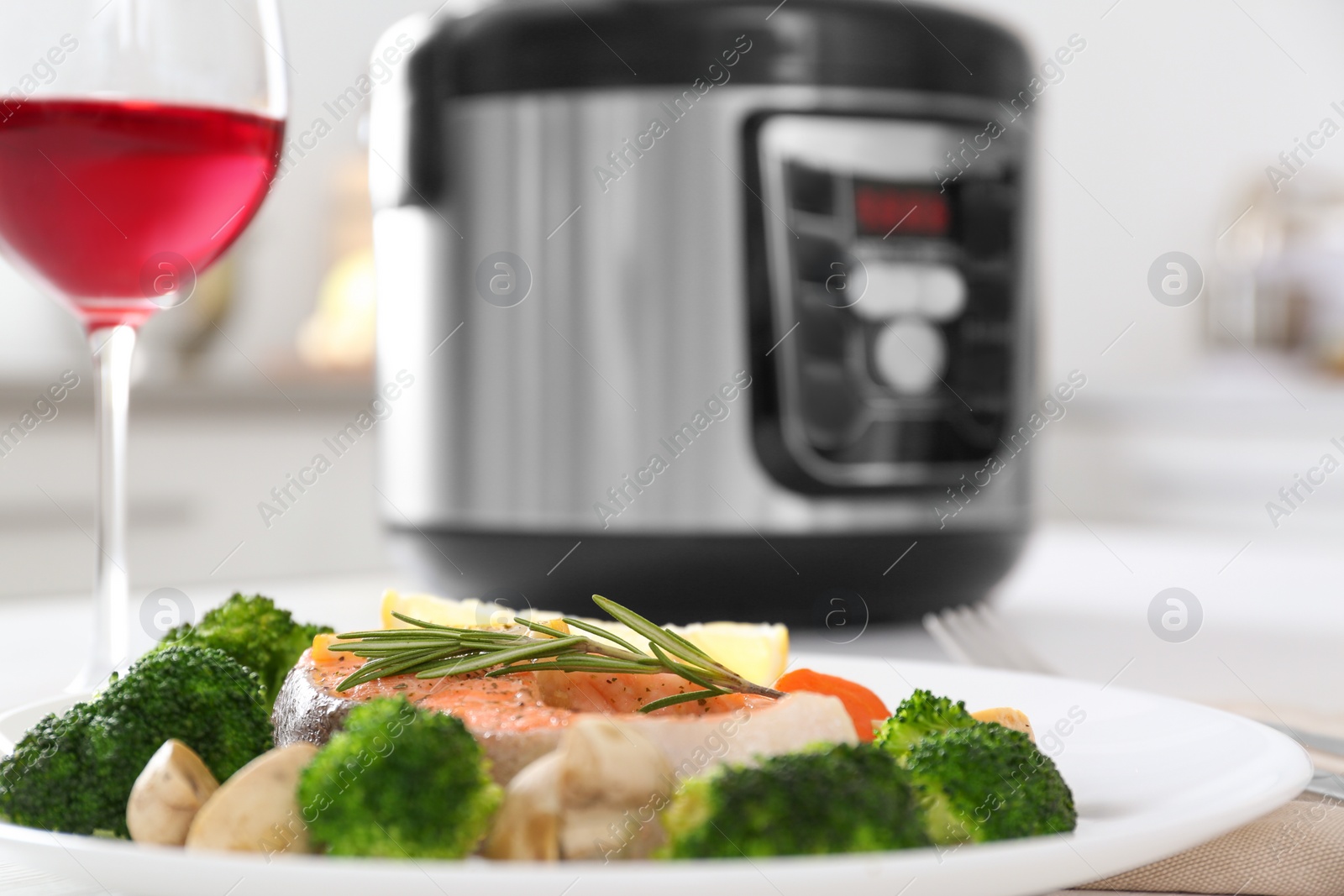 Photo of Plate with salmon steak and garnish prepared in multi cooker on table