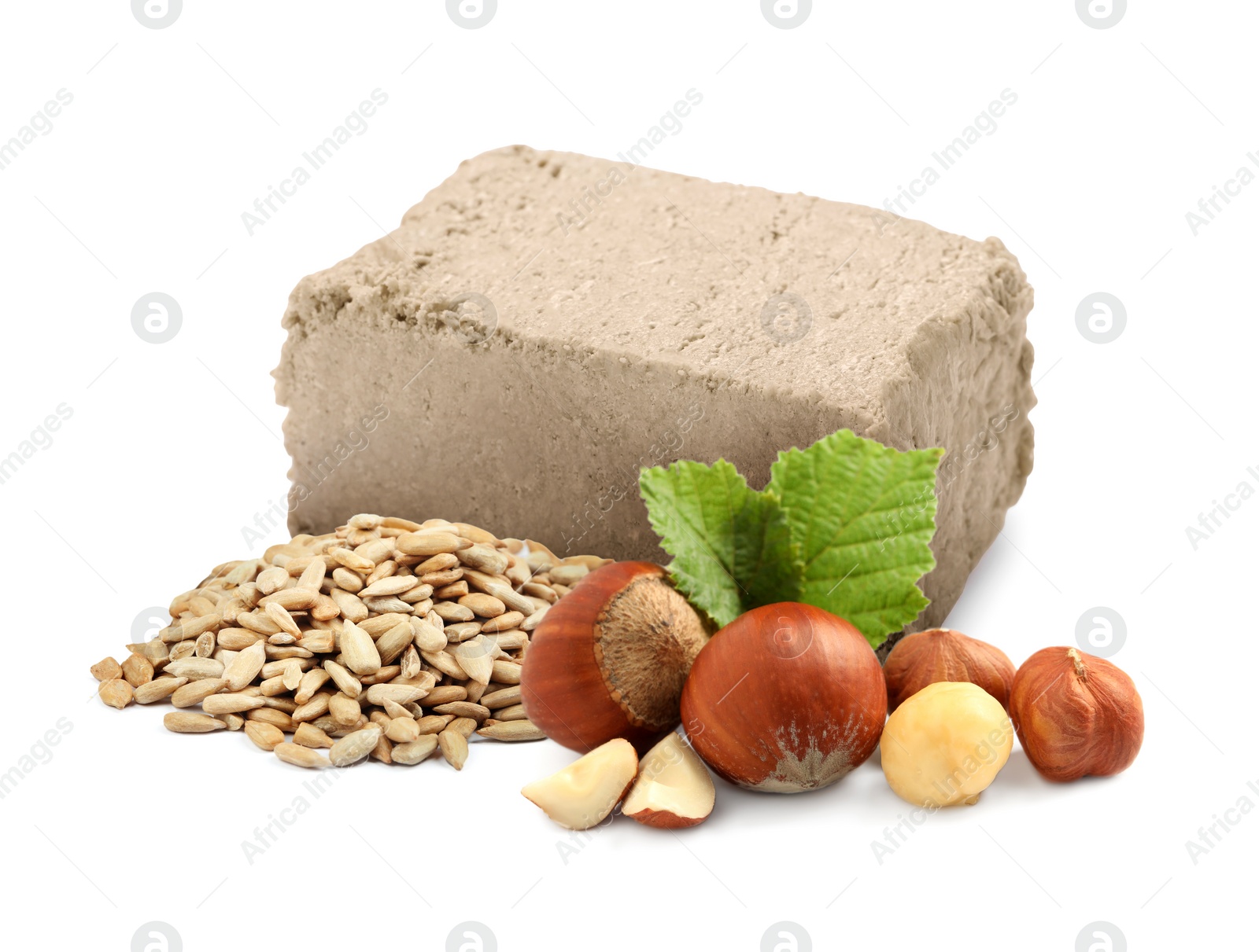 Image of Tasty halva, peeled sunflower seeds, hazelnuts and green leaves isolated on white