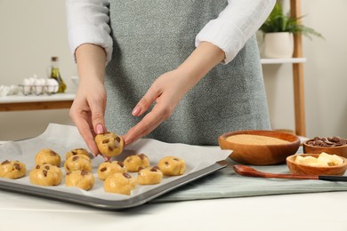 Photo of Woman preparing chocolate chip cookies at white table in kitchen, closeup