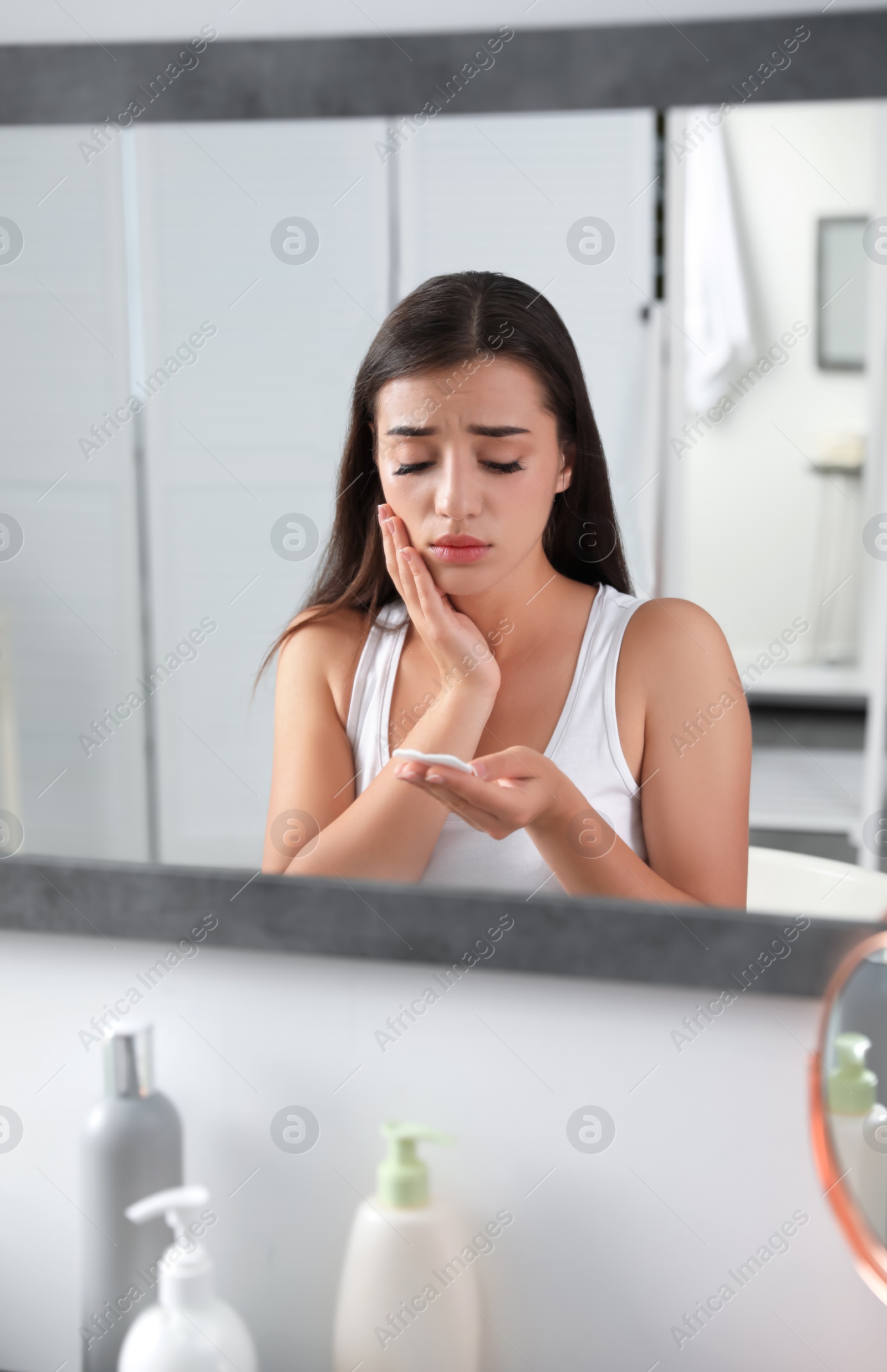 Photo of Young woman with eyelash loss problem near mirror indoors