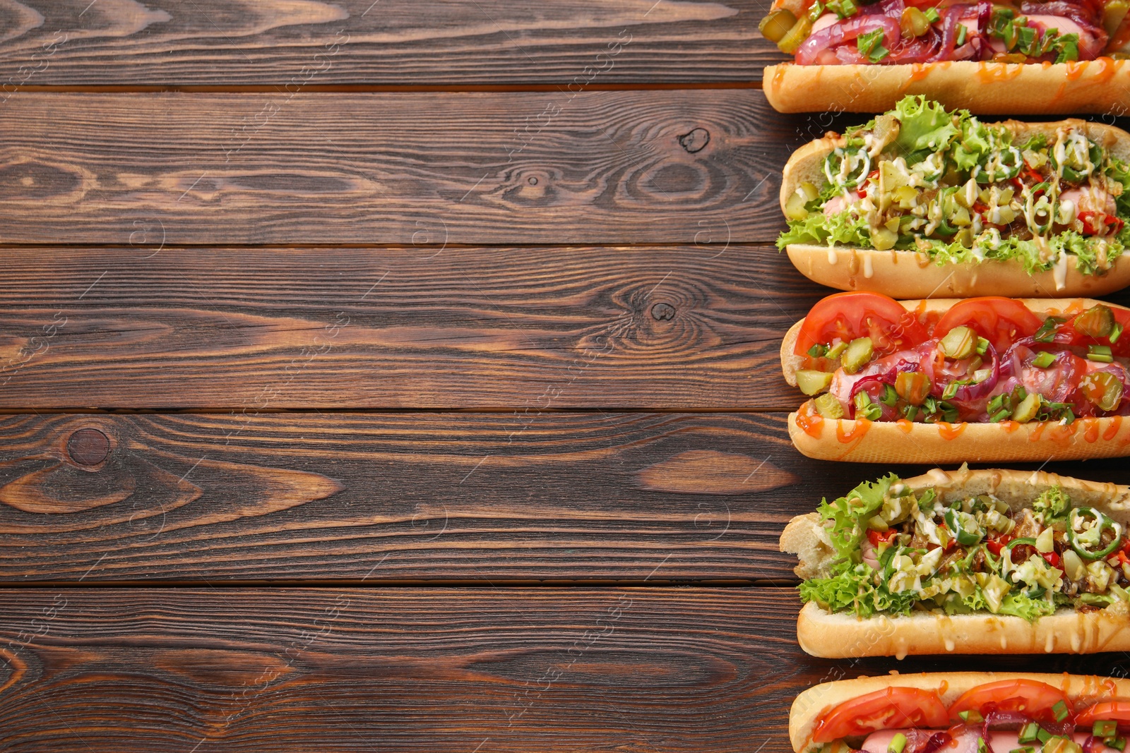 Photo of Different tasty hot dogs on wooden table, flat lay. Space for text