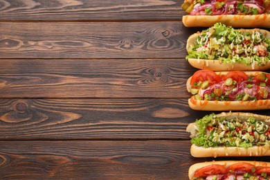 Different tasty hot dogs on wooden table, flat lay. Space for text