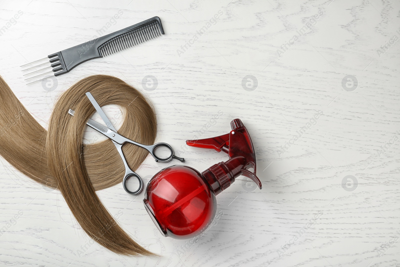 Photo of Flat lay composition with hair lock and tools on wooden background. Space for text