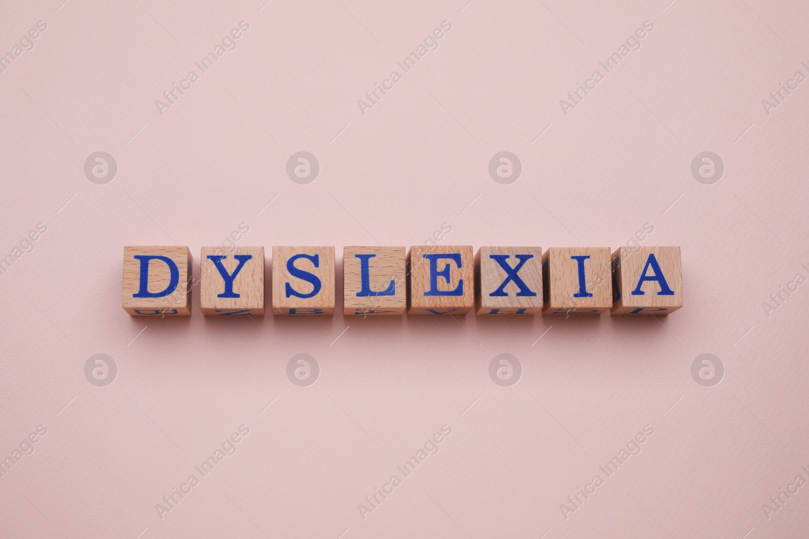 Photo of Wooden cubes with word Dyslexia on beige background, flat lay