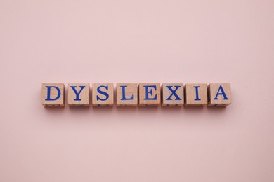 Photo of Wooden cubes with word Dyslexia on beige background, flat lay