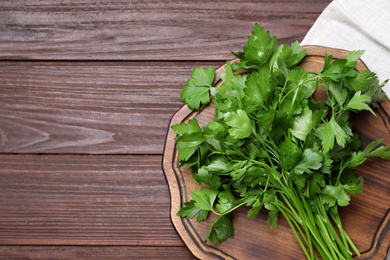 Photo of Bunch of fresh green parsley on wooden table, top view. Space for text