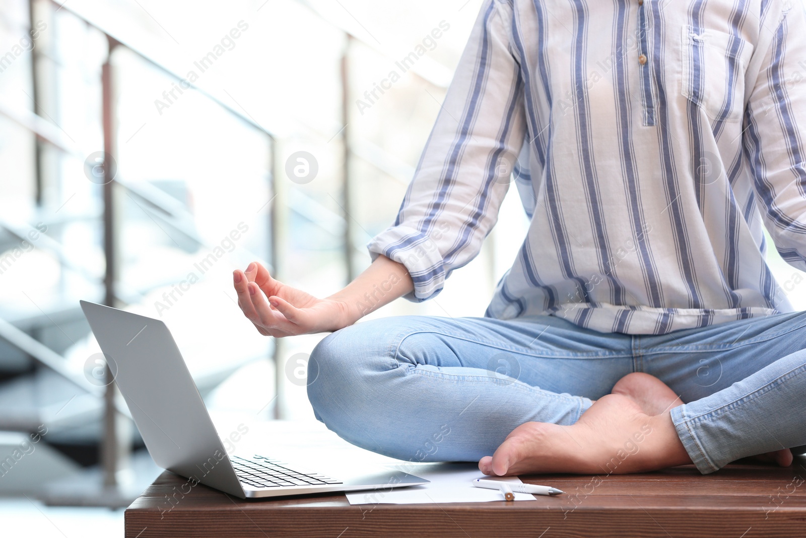 Photo of Woman meditating on table in office during break, closeup. Zen yoga