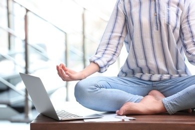 Woman meditating on table in office during break, closeup. Zen yoga