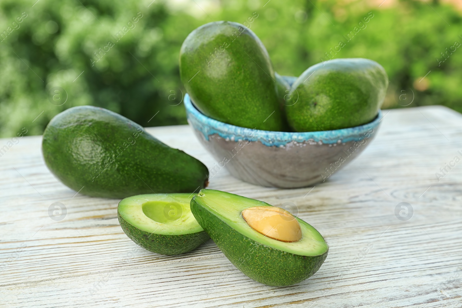 Photo of Ripe avocados on wooden table against blurred background