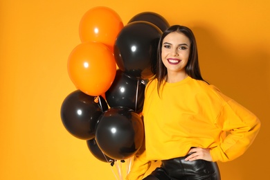 Photo of Beautiful woman with balloons on yellow background. Halloween party