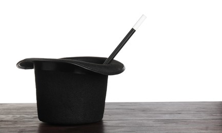 Photo of Magician's hat and wand on wooden table against white background