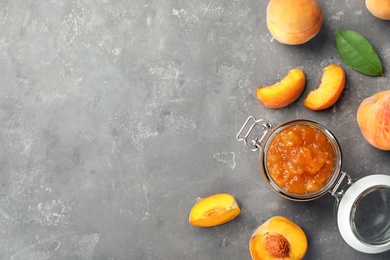 Photo of Flat lay composition with jar of tasty peach jam and fresh fruit on gray table