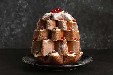 Photo of Delicious Pandoro Christmas tree cake with powdered sugar and berries on black table