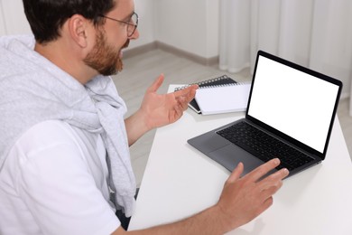 Photo of Man having video chat via laptop at white table indoors, selective focus