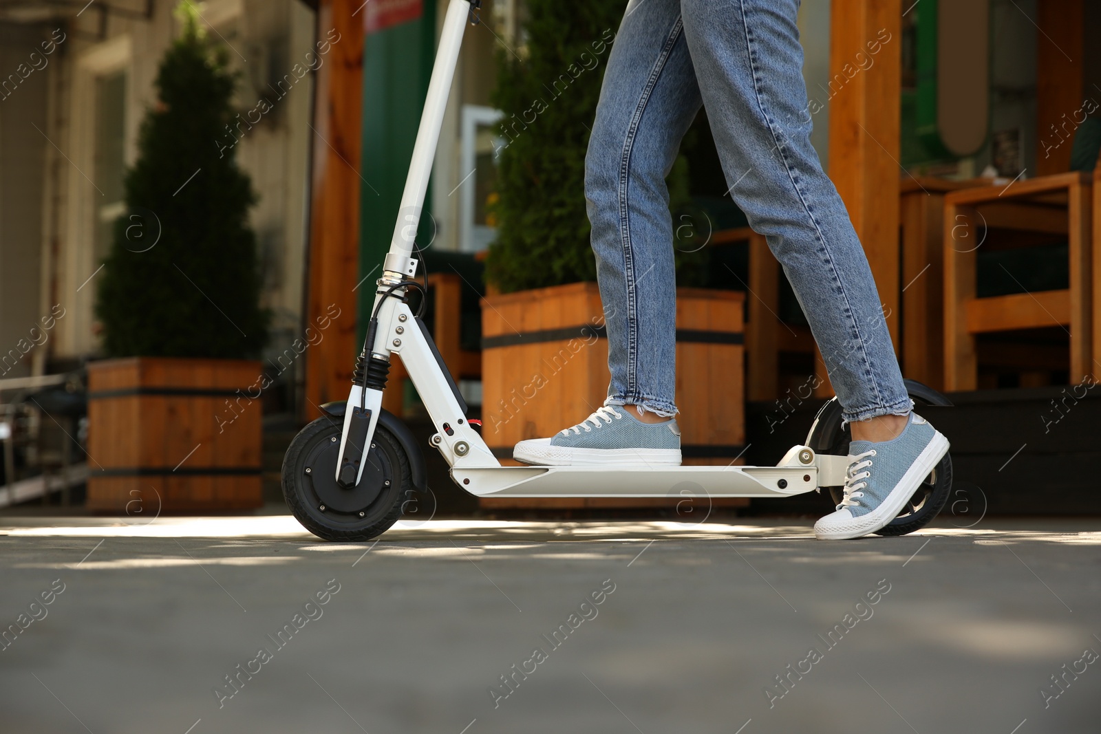 Photo of Woman riding electric kick scooter outdoors, closeup