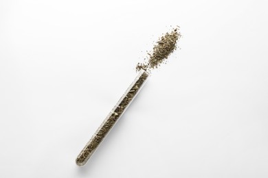 Glass tube with dry thyme on white background, top view