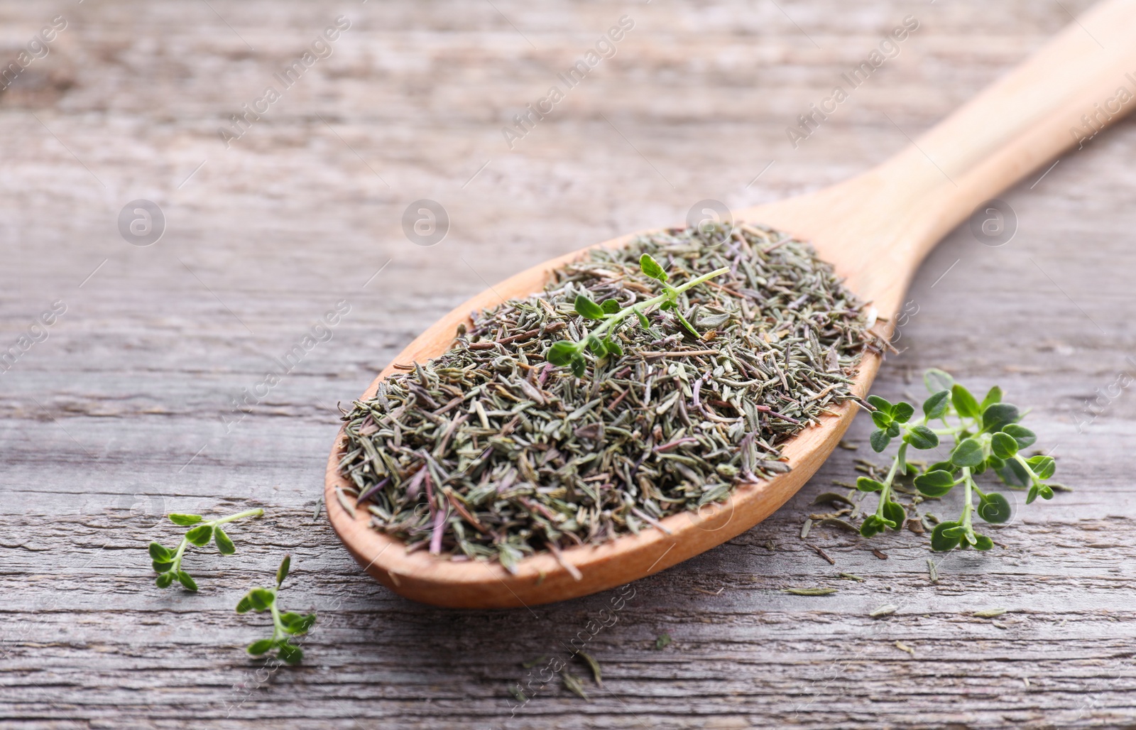 Photo of Spoon with dried and fresh thyme on wooden table, closeup