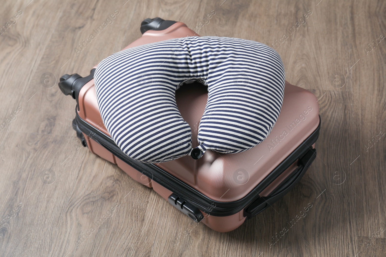 Photo of Striped travel pillow and suitcase on floor