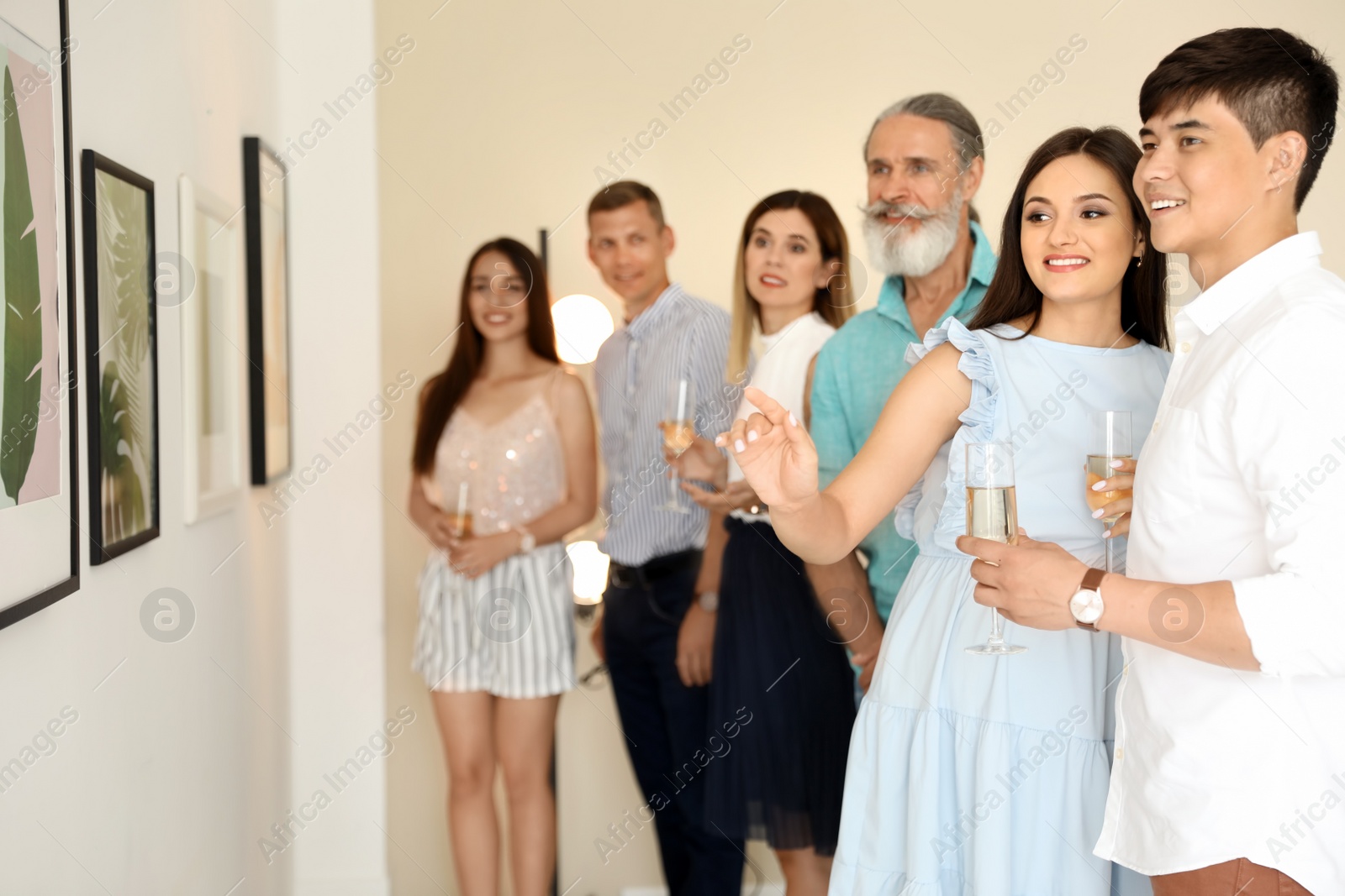 Photo of Group of people with glasses of champagne at exhibition in art gallery