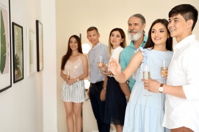 Photo of Group of people with glasses of champagne at exhibition in art gallery