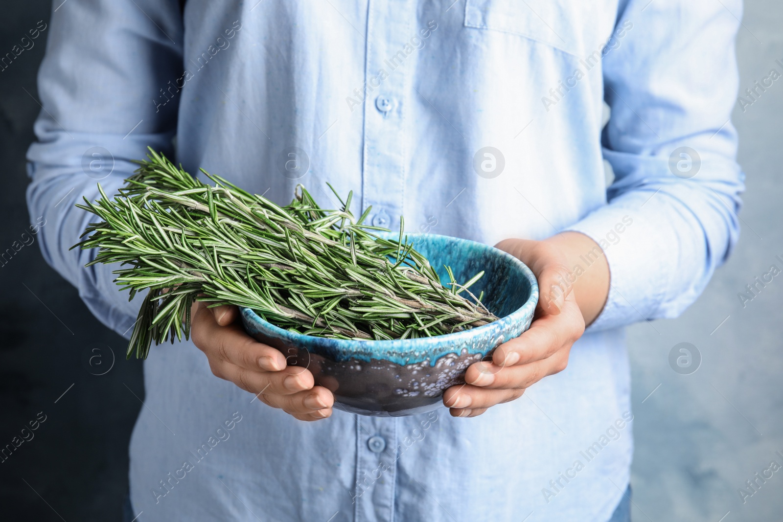 Photo of Young woman holding bowl of fresh rosemary, closeup