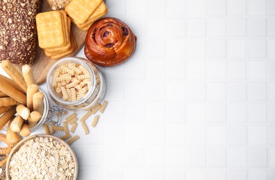 Photo of Different gluten free products on white tiled table, flat lay. Space for text
