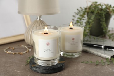 Photo of Burning soy candles with wooden wicks and decor on grey table