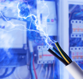 Sparking cables against blurred electric cabinet, closeup