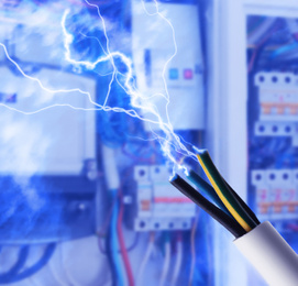 Image of Sparking cables against blurred electric cabinet, closeup