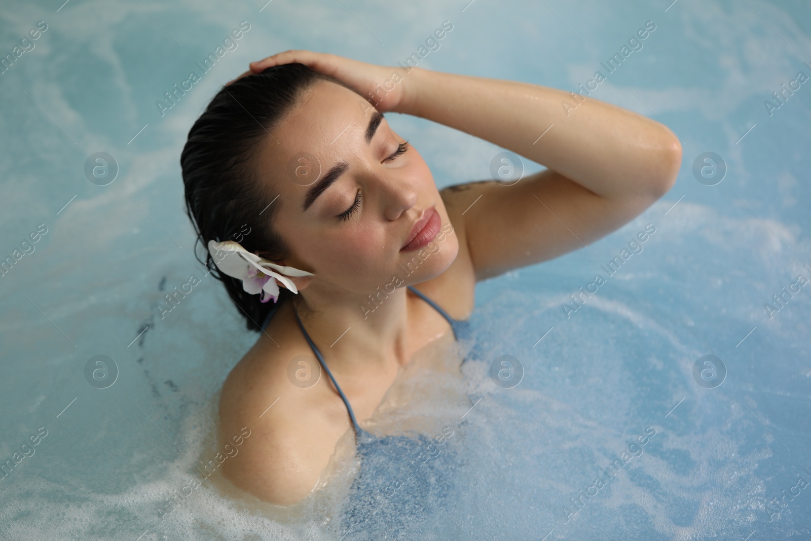 Photo of Beautiful woman with orchid flower in spa swimming pool