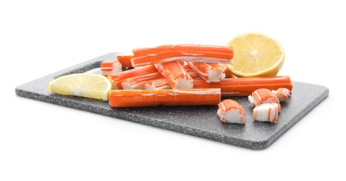 Photo of Black board with delicious crab sticks and lemon isolated on white