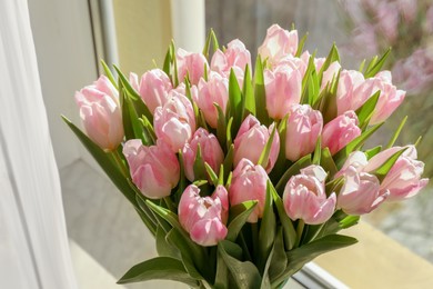 Spring is coming. Bouquet of beautiful tulip flowers in glass vase on windowsill indoors, closeup
