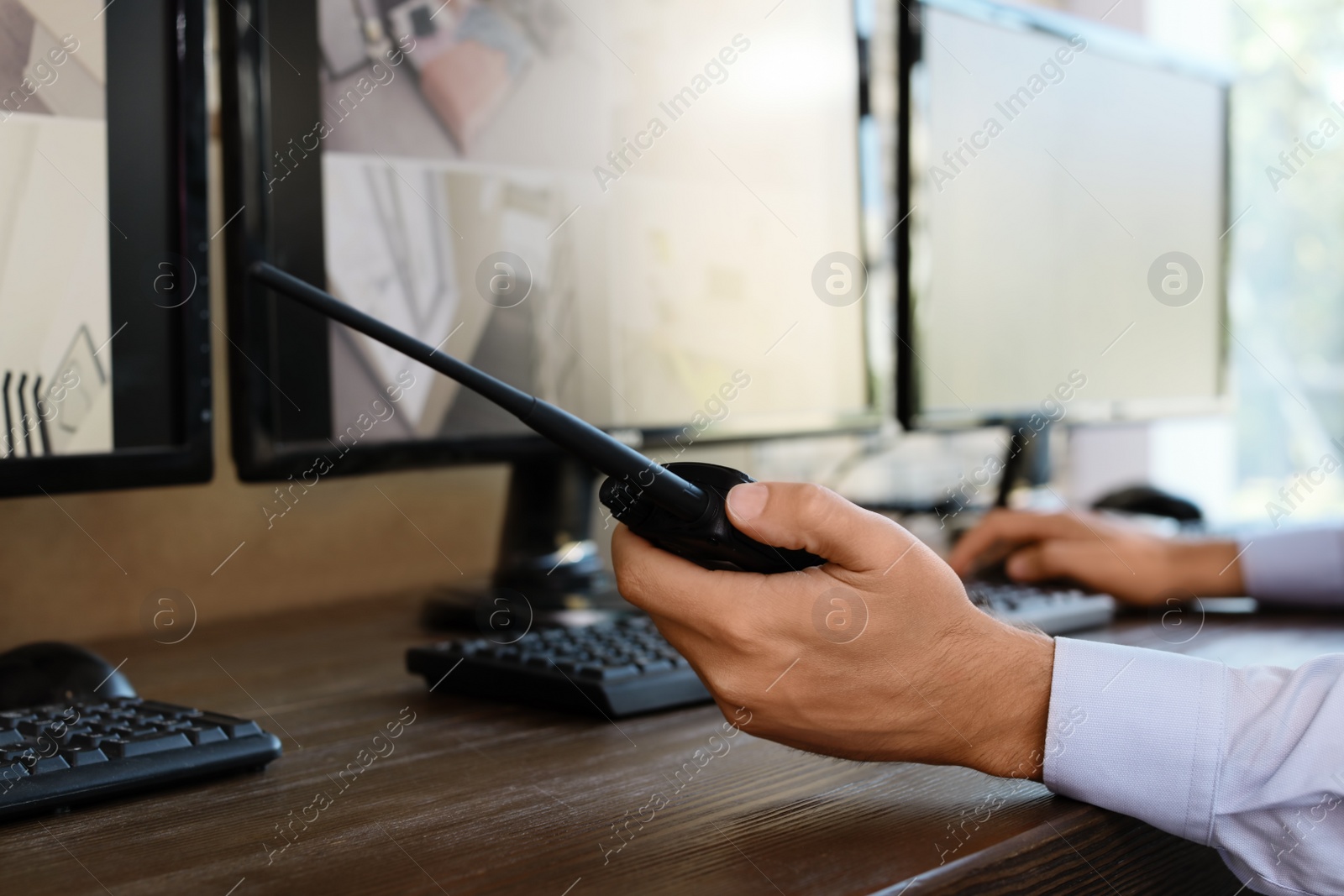 Photo of Male security guard with portable transmitter at workplace, closeup. CCTV surveillance