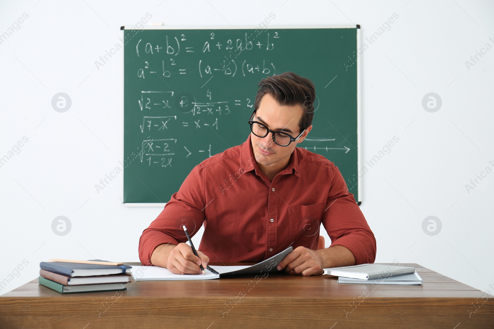 Photo of Young teacher working at table in classroom