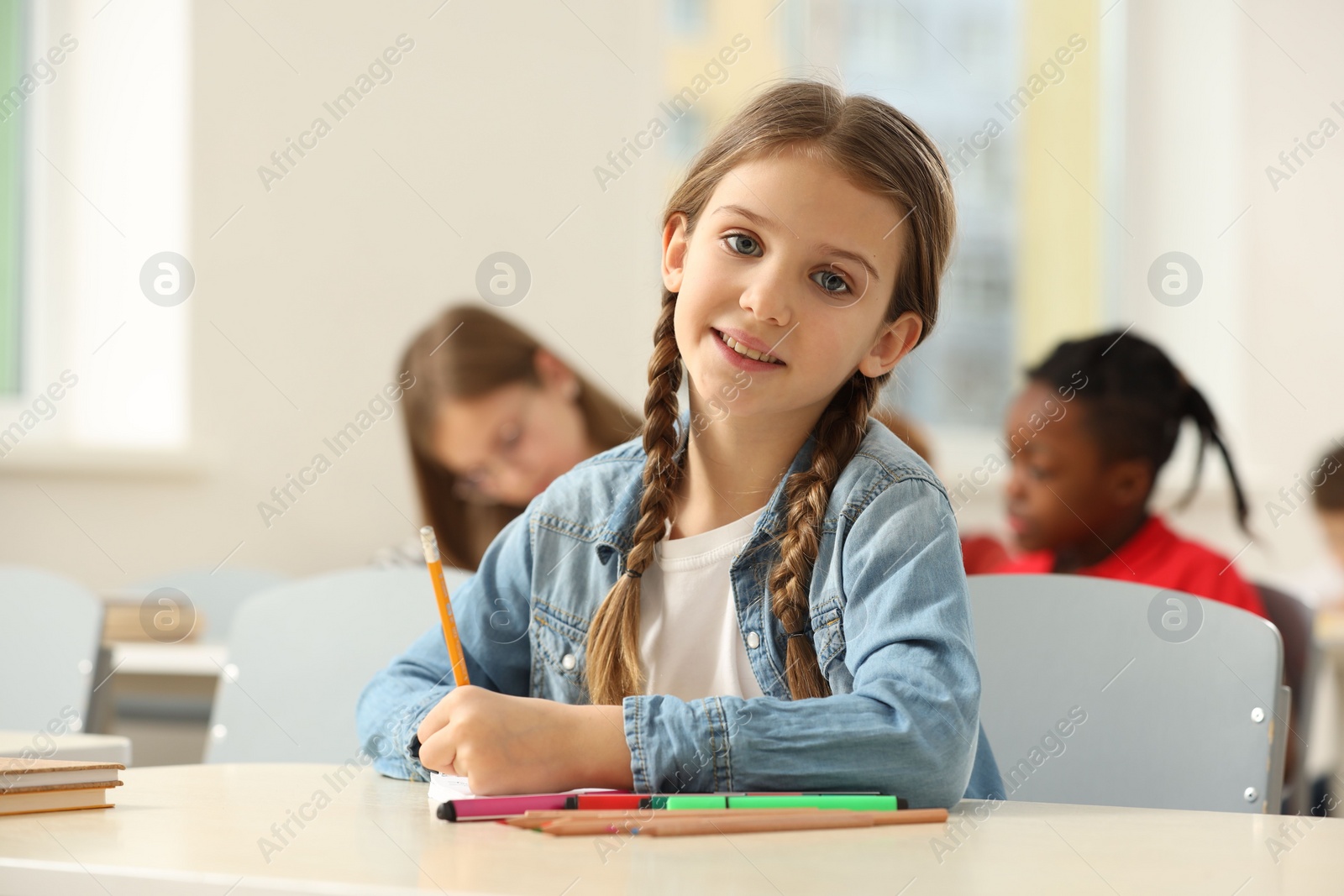 Photo of Portrait of smiling little girl studying in classroom at school