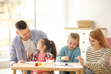 Photo of Lovely family painting at table indoors. Playing with children