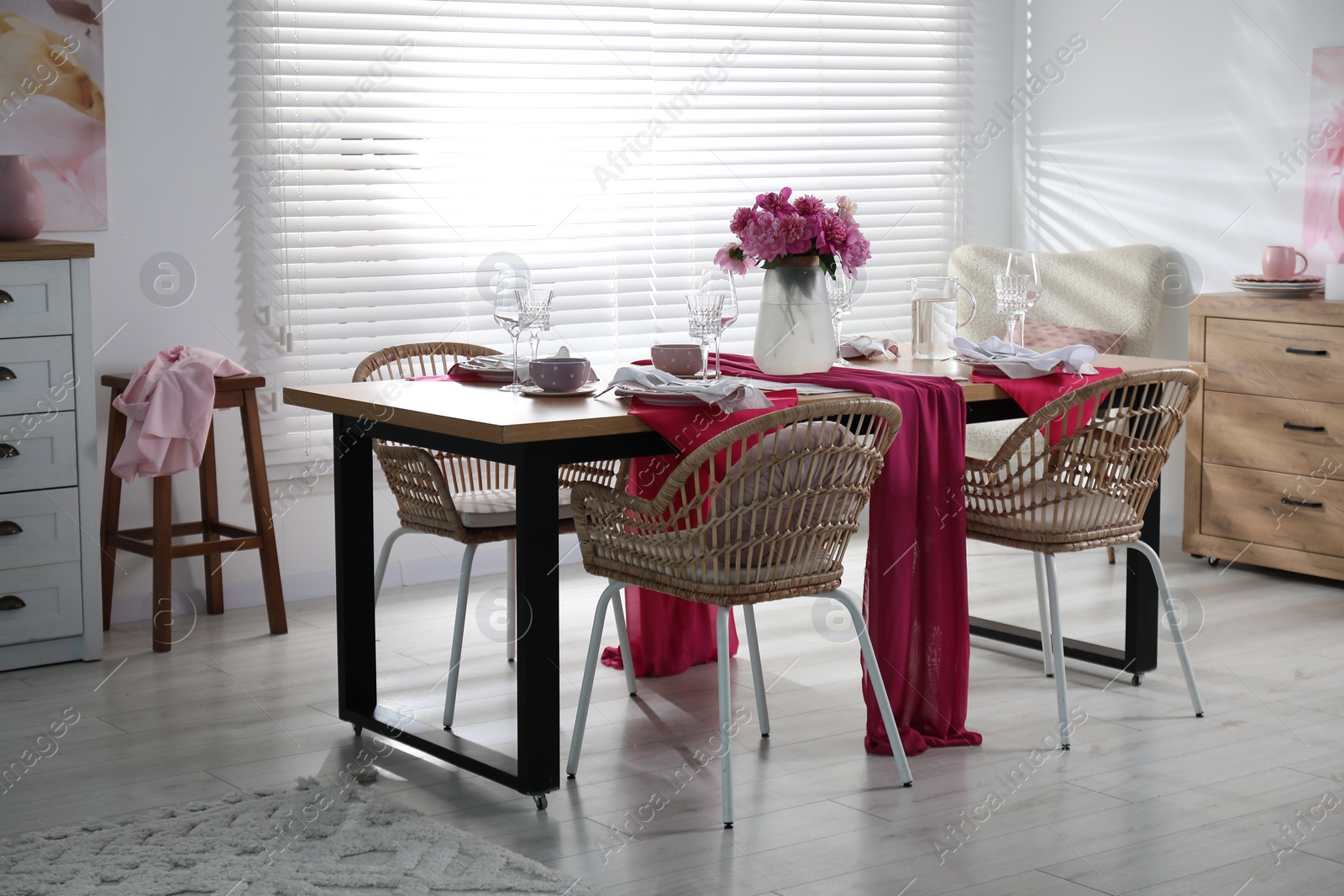 Photo of Pink peonies on table with beautiful setting and rattan chairs in dining room